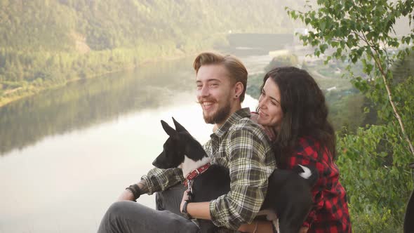 Young Couple of Tourists with Their Dog Resting on the Mountain