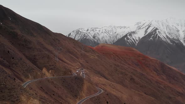 Panoramic Aerial View of Curved Road on Mountain Pass with Large Trucks Passing Along It Against