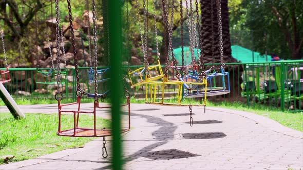 Wide shot of empty swings in an amusement park