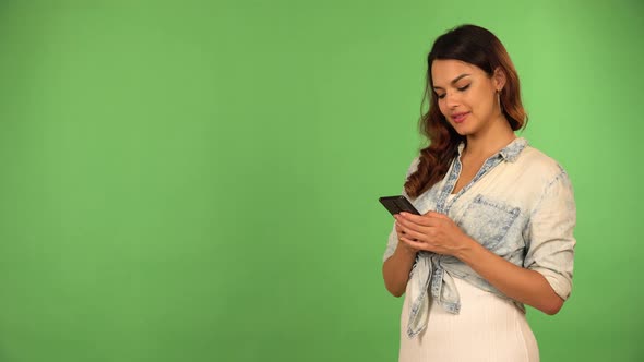 A Young Beautiful Caucasian Woman Works on a Smartphone with a Smile  Green Screen Background