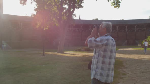 Old Man Takes Photos of Wooden Fortress in Outdoor Museum