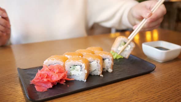 Unrecognizable Woman Dipping Roll in Soy Sauce