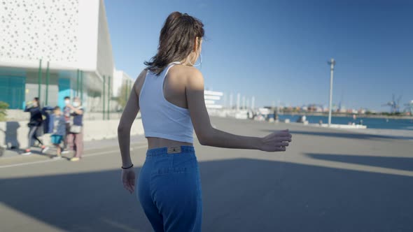 Darkhaired Girl Spins Around on Rollerskates By Boats in Sunny Marina