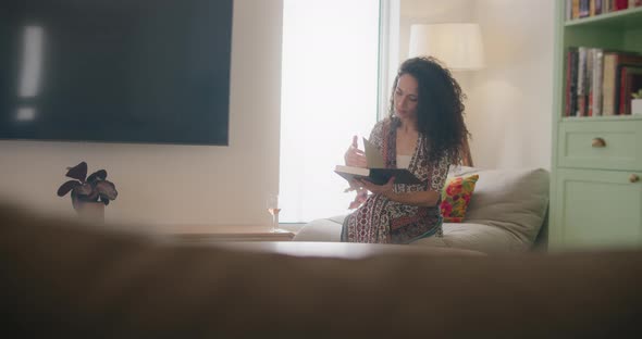 Woman in dress reading a book on a couch