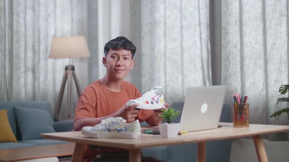 Asian Boy Footwear Designer Smiling To The Camera While Working On A Laptop At Home