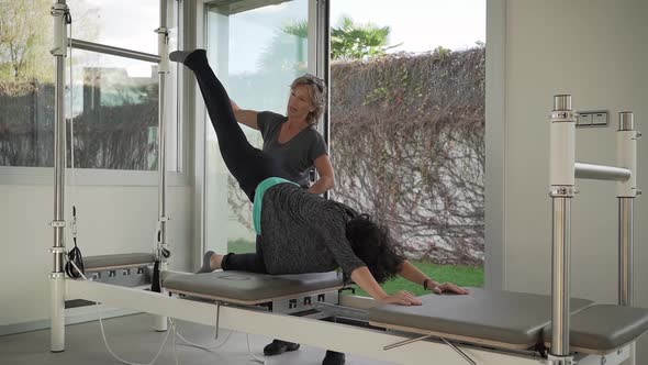 Woman doing yoga with help of trainer