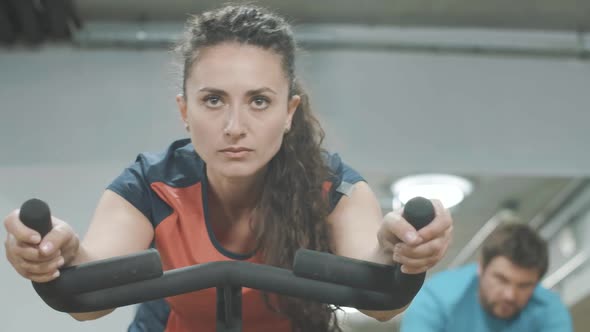 Middle Shot of Focused Concentrated Sportswoman Cycling in Sports Club on Exercise Bike. Young Slim