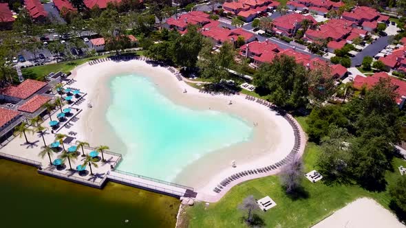 Aerial descent into front of lake clubhouse at a community sand lagoon pool