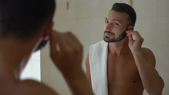 Man Cleaning Ear With Cotton Swab in Bathroom, Morning Procedure, Healthcare