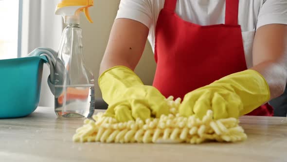 Woman in an Apron and Protective Gloves Washes and Polishes the Countertop Thoroughly