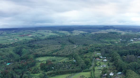 Wide aerial dolly shot of rural rainforest and farmland on the Big Island of Hawaii. 4K