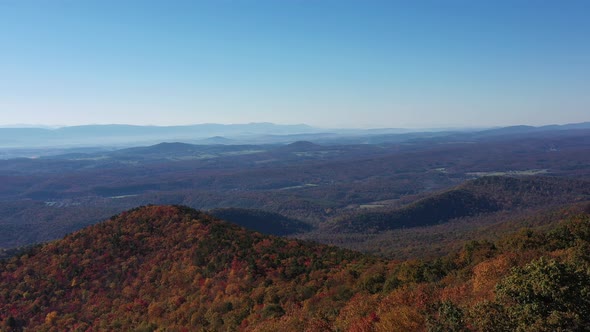 An aerial shot (dolly out) of Tibbet Knob and the Shenandoah Valley in Autumn. Red, Orange and Yello