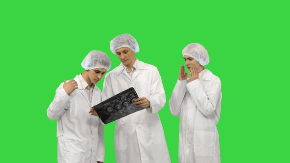 Three Doctors Rhythmically Look at an X-ray Photo of a Patient Together on a Green Screen, Chroma