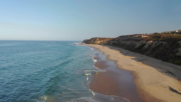 Stunning 4k drone aerial of crashing waves on the beach coastline of stunning Orange County.