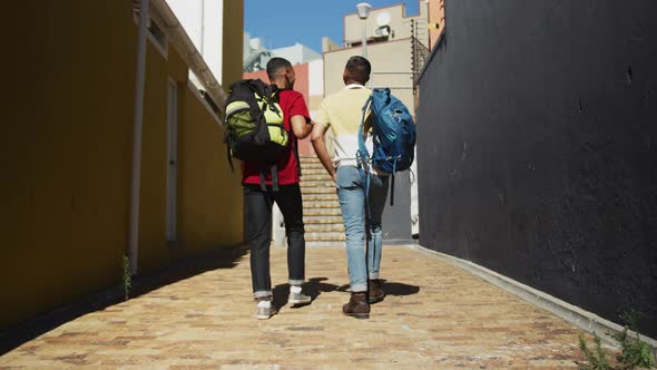 Back view of two mixed race male friends walking in the street