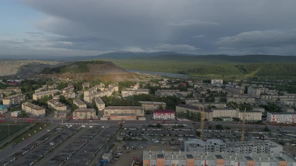 Aerial view of city with low buildings. Near the city a huge quarry and ore dumps