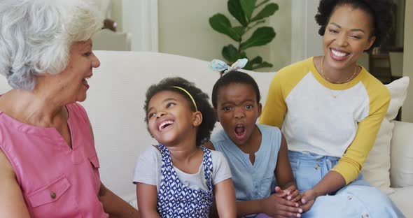 Portrait of happy african american grandmother with adult daughter and granddaughters in living room