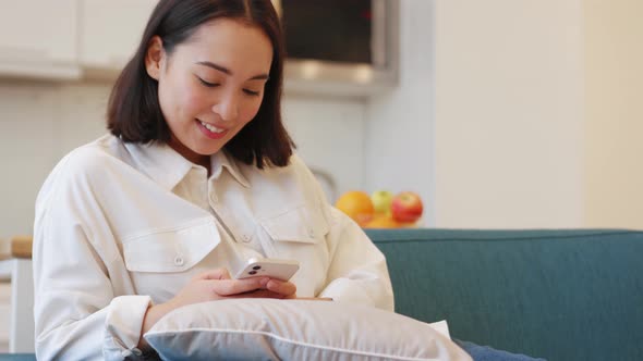 Happy Asian woman texting by phone