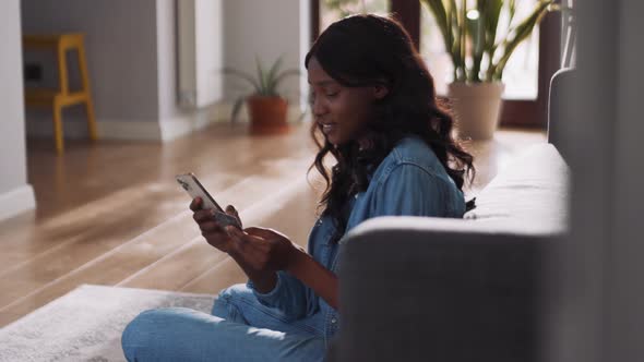 Smiling African woman entering bank card number at phone