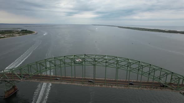 An aerial view of the Fire Island Inlet Bridge during a cloudy morning with calm waters. The drone c