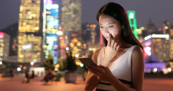 Woman looking at mobile phone in the city at night 