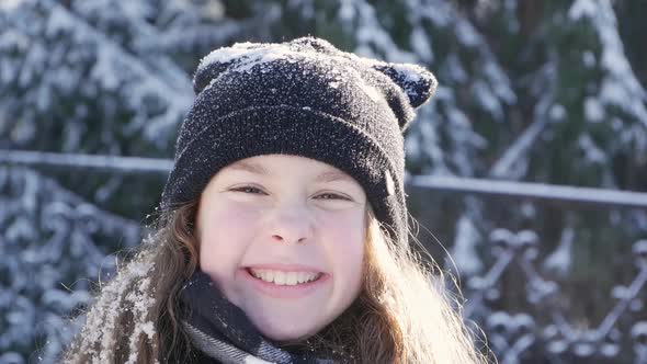 Cute Young Girl Blowing Snowflakes Into Camera. Wintertime