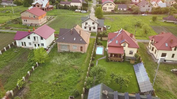 Aerial view of suburban homes and private house with green grass covered yard, solar panels on roof,