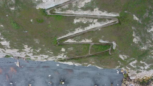 Top down aerial shot from cliffside pathway to the blue sea white cliffs of dover