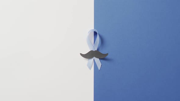 Video of paper moustache and pale blue prostate cancer ribbon on white and blue background