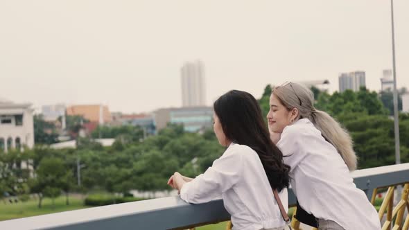 Asian lesbian couples enjoying traveling and talk while standing on the bridge.