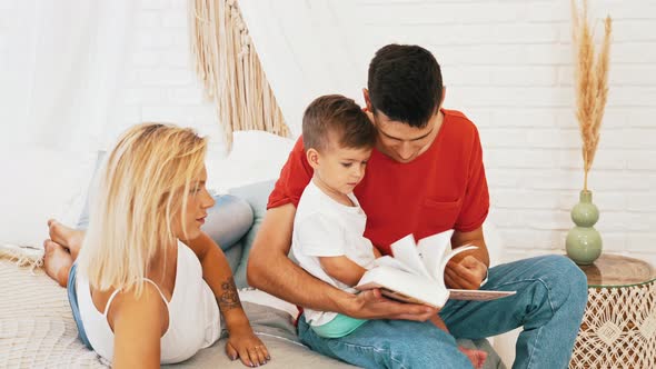 Little Boy Reading a Book with His Parents at Home