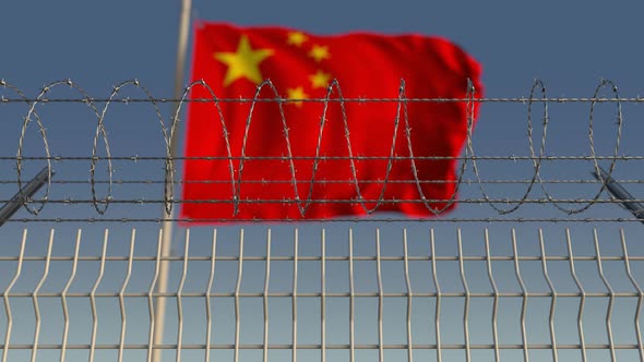 Waving Flag of China Behind Barbed Wire Fence