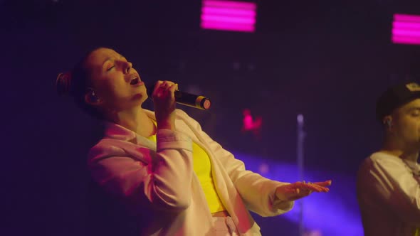 Young Woman Singer in White Clothes Emotionally Sings and Dancing on the Stage at Live Concert