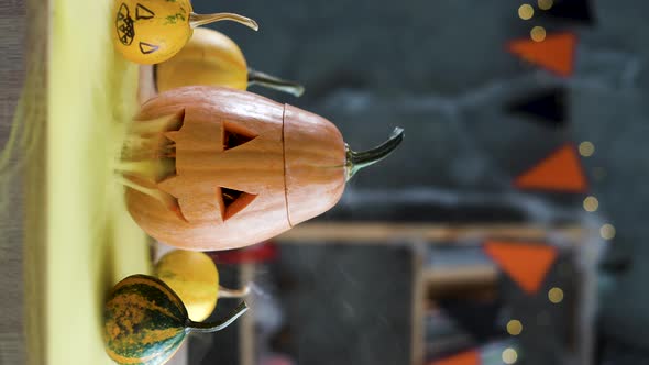 A Carved Halloween Pumpkin Lantern on a Table with Yellow Smoke at the Top