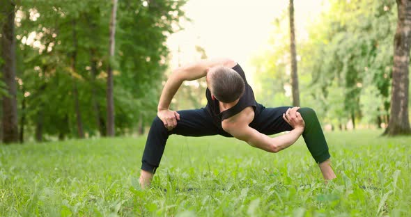 Men Practicing Yoga and Meditating in Park at Sunny Summer Day