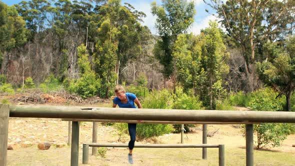 Fit man and woman climb a hurdles during obstacle course