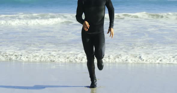 Male surfer running in the beach