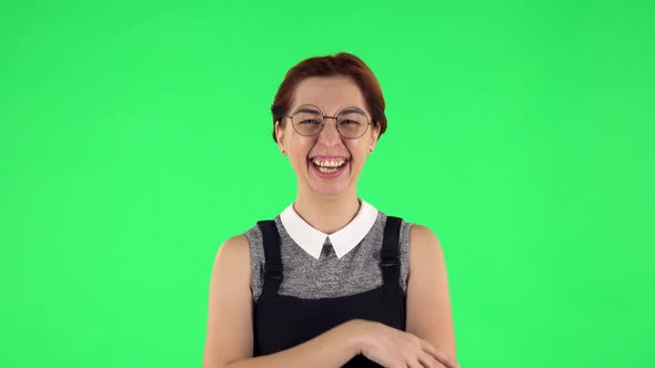 Portrait of Funny Girl in Round Glasses Communicates with Someone in a Friendly Manner. Green Screen