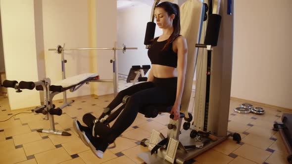 Wide Shot of Concentrated Gorgeous Slender Sportswoman Training Leg Muscles Using Exercise Machine