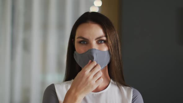 Portrait of caucasian woman with straight hair taking off grey face mask