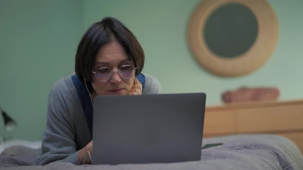 Meditative mature woman texting by laptop