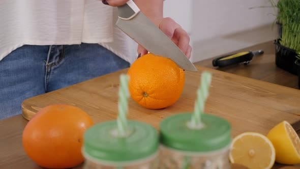 Closeup of a Woman Cutting Oranges on a Wooden Cutting Board