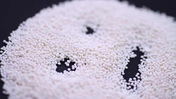The Face Is Laid Out of White Granules on a Black Background. Closeup Rotation