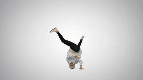 Male Doctor in White Robe and Protective Cap Dancing Breakdance on His Head and Arms on Gradient