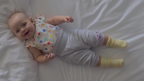 A Smiling Six Months Baby Girl Lying on a Bed