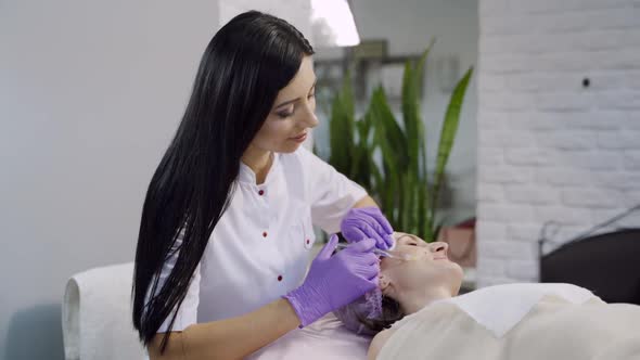 A beautician makes biorevitalization on the client's face in the beauty salon