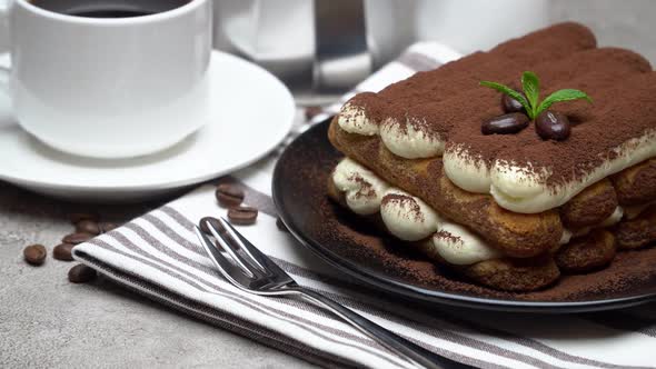 Classic Tiramisu Dessert on Ceramic Plate, Milk or Cream and Cup of Coffee on Concrete Background