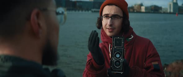 Young man with glasses giving directions to model while he takes shots with vintage camera