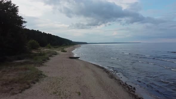 Aeral view of beach and sea with rain clouds. Coastline perspective with rolling waves.