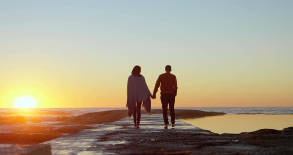 Rear view of couple walking on pier 4k